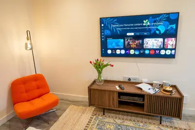 a living room with an orange chair and a flat screen tv at Cosy & Contemporary 2 Bed Home, Quiet Area Parking - Pass the Keys in Shrewsbury