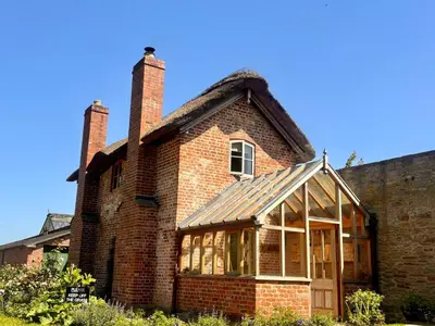 a brick house with two chimneys on top of it at Cosy Cottage with Log Fire Near Hay-on-Wye in Almeley