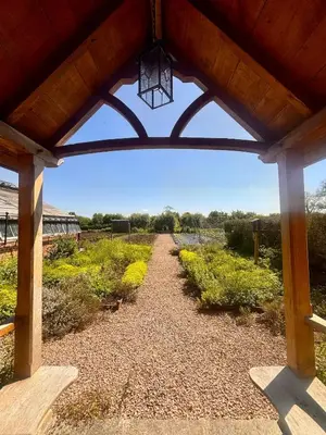 a view of a pathway through a wooden pergola at Cosy Cottage with Log Fire Near Hay-on-Wye in Almeley