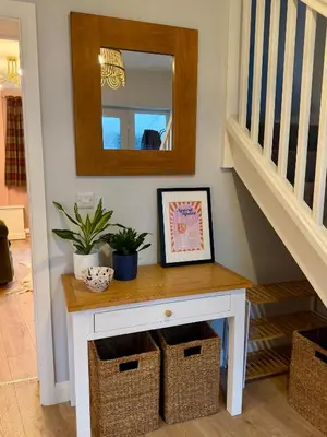 a white console table with baskets and a mirror at Unique Vicarage Town Cottage in Leominster