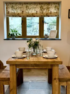 a wooden table with dishes and flowers on it at Y Beudy Bach in Llanfor