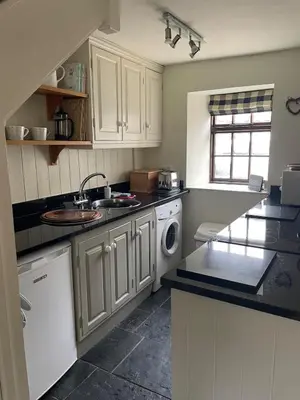 a kitchen with white cabinets and a sink and a dishwasher at Cosy River Cottage in Brecon with a Fireplace in Merthyr Cynog