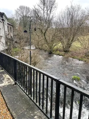 a river with a fence next to a river with snow at Cosy River Cottage in Brecon with a Fireplace in Merthyr Cynog