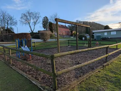 a wooden fence with a playground in a park at The Little lodge on the lake in Welshpool