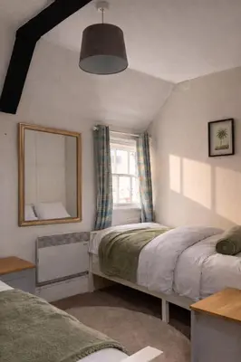 a bedroom with two beds and a mirror and a window at Cosy Town centre Historic Tudor Cottage & parking sleeps 6 in Shrewsbury