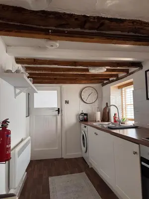 a kitchen with white cabinets and a clock on the wall at Cosy Town centre Historic Tudor Cottage & parking sleeps 6 in Shrewsbury