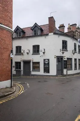 a white building on the corner of a street at Cosy Town centre Historic Tudor Cottage & parking sleeps 6 in Shrewsbury