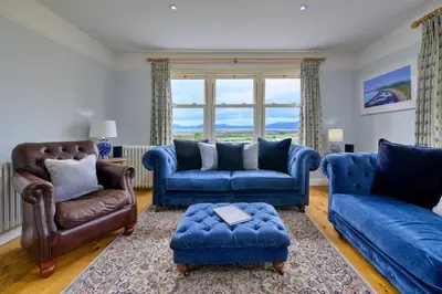 a living room with blue furniture and a large window at Finest Retreats - Bryn Awelon in Harlech