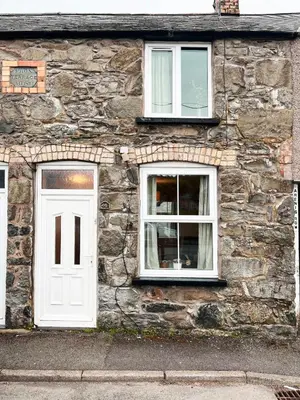 a stone building with a white door and two windows at Arenig Cottage, a Snowdonia retreat near Lake Bala in Bala