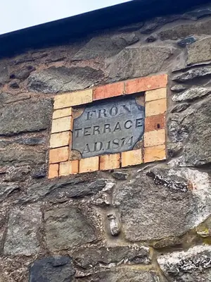 a sign on the side of a stone building at Arenig Cottage, a Snowdonia retreat near Lake Bala in Bala
