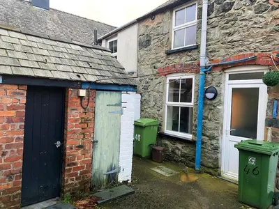 an old brick house with a garage and a door at Arenig Cottage, a Snowdonia retreat near Lake Bala in Bala