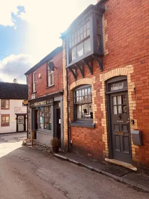 a brick building with a balcony on top of it at Cosy, quirky Victorian house on Waterfall Street in Llanrhaeadr-ym-Mochnant