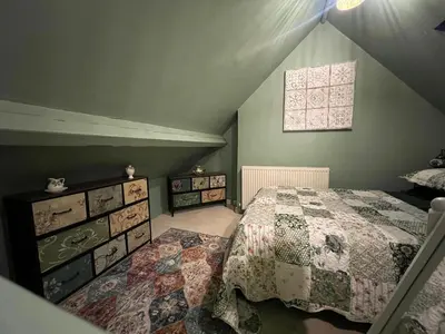 a attic bedroom with a bed and a window at Cosy, quirky Victorian house on Waterfall Street in Llanrhaeadr-ym-Mochnant