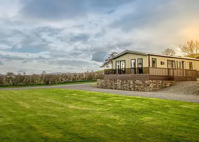 a large house with a porch and a grass field at Rockbridge Country Park in Presteigne