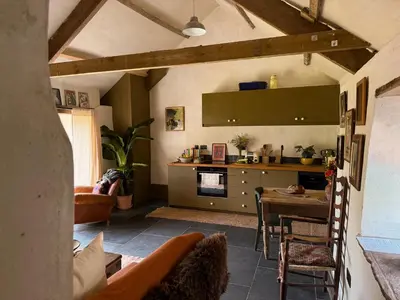 a living room with a table and a kitchen at Y Beudy - A Converted Barn in the Brecon Beacons in Brecon
