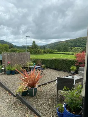 a garden with a table and chairs and plants at Rosehill annexe in Knighton