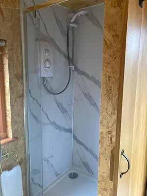 a shower with a glass door in a bathroom at Bijou Cabin in Ludlow