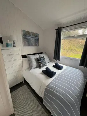 a bedroom with a bed with two blue towels on it at Welsh Coast Seaview 2 Bedroom Wooden Lodge at Clarach Bay in Aberystwyth