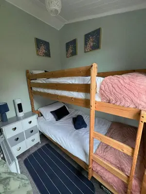 a bedroom with two bunk beds and a night stand at Welsh Coast Seaview 2 Bedroom Wooden Lodge at Clarach Bay in Aberystwyth