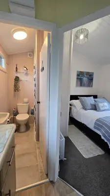 a bedroom with a bed and a bathroom with a sink at Welsh Coast Seaview 2 Bedroom Wooden Lodge at Clarach Bay in Aberystwyth