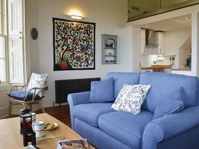 a blue couch in a living room with a table at Sea View in Rhyd-y-felin