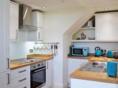 a kitchen with white cabinets and a sink and a microwave at Sea View in Rhyd-y-felin