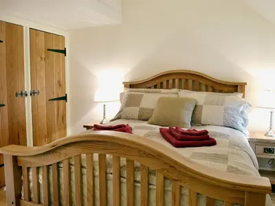 a large wooden bed in a bedroom with two lamps at Golygfar Mynydd - Mountain View in Strata Florida