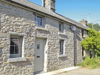 a stone house with a white door and windows at Ivy Bush Cottage in Llanddewi-Brefi