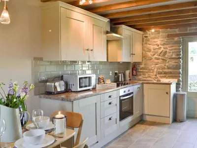 a kitchen with white cabinets and a table with a microwave at Ivy Bush Cottage in Llanddewi-Brefi