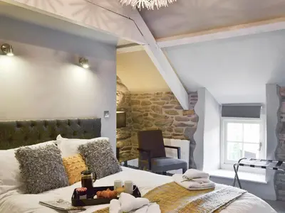 a bedroom with a large bed with a stone wall at Ivy Bush Cottage in Llanddewi-Brefi