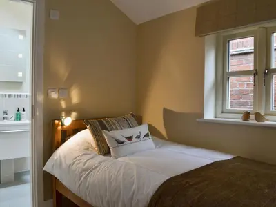 a bedroom with a bed with white sheets and a window at Red Lion Lodge in Myddle
