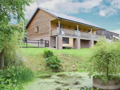 a large house with a balcony on the side of it at The Lodge in Presteigne
