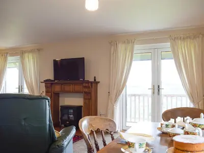 a living room with a table with chairs and a television at The Lodge in Presteigne
