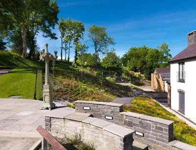 a garden with a stone wall and a monument at Y Talbot in Tregaron