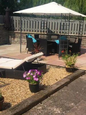 a patio with a table and chairs and flowers at Sound of the River in Talgarth