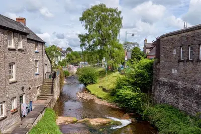 a river between two brick buildings in a town at Sound of the River in Talgarth