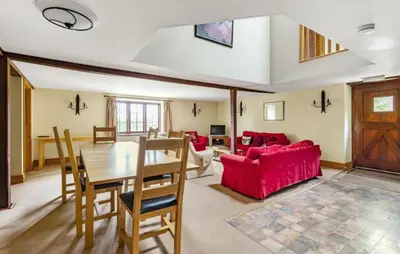 a living room with a table and a red couch at Brynderwen Barn in Llangorse