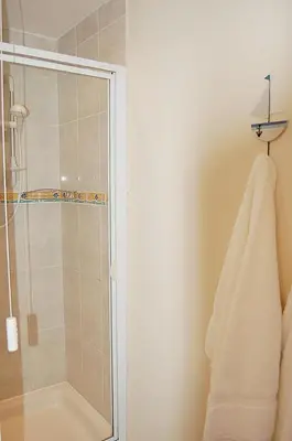 a bathroom with a shower with a glass door at Saint Cadfans Lodge in Tywyn