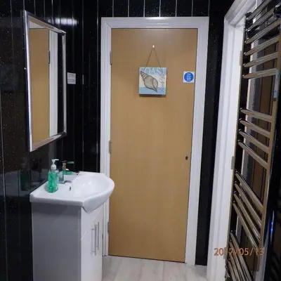 a bathroom with a sink and a wooden door at Saint Cadfans Lodge in Tywyn