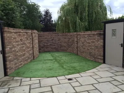a garden with a brick fence and green grass at Shrewsbury Cottage in Shrewsbury
