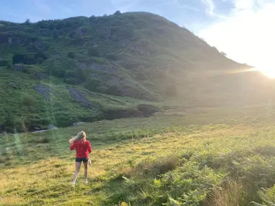 a woman standing in a field with a mountain at Bronfelin & Troed-y-Rhiw Holiday Cottage in Llanwrtyd Wells