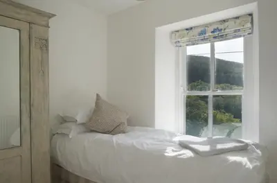 a white bedroom with a bed and a window at Bronfelin & Troed-y-Rhiw Holiday Cottage in Llanwrtyd Wells