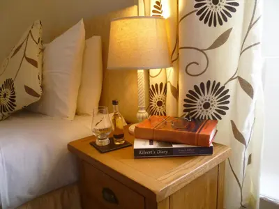a bed with a table with a lamp and books at Aberllynfi Riverside Guest House in Glasbury