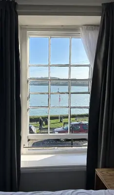 a window in a bedroom with a view of the ocean at Hotel Penwig in New Quay