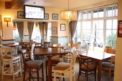 a restaurant with tables and chairs and a television at Hotel Penwig in New Quay