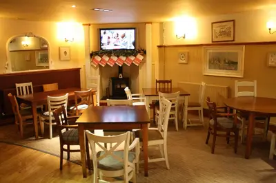 a restaurant with tables and chairs and a television at Hotel Penwig in New Quay