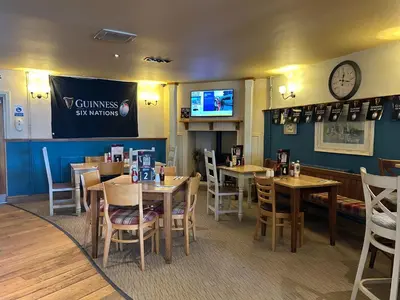 a restaurant with tables and chairs and a clock on the wall at Hotel Penwig in New Quay