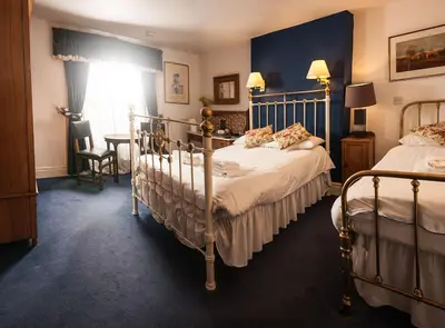 a bedroom with two beds and a table and a window at Gales Of Llangollen in Llangollen