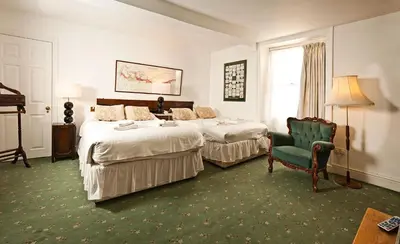 a hotel room with two beds and a chair at Gales Of Llangollen in Llangollen