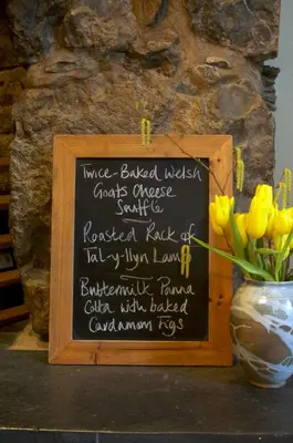 a chalkboard sign with a vase of yellow flowers at Dolffanog Fawr in Tal-y-llyn